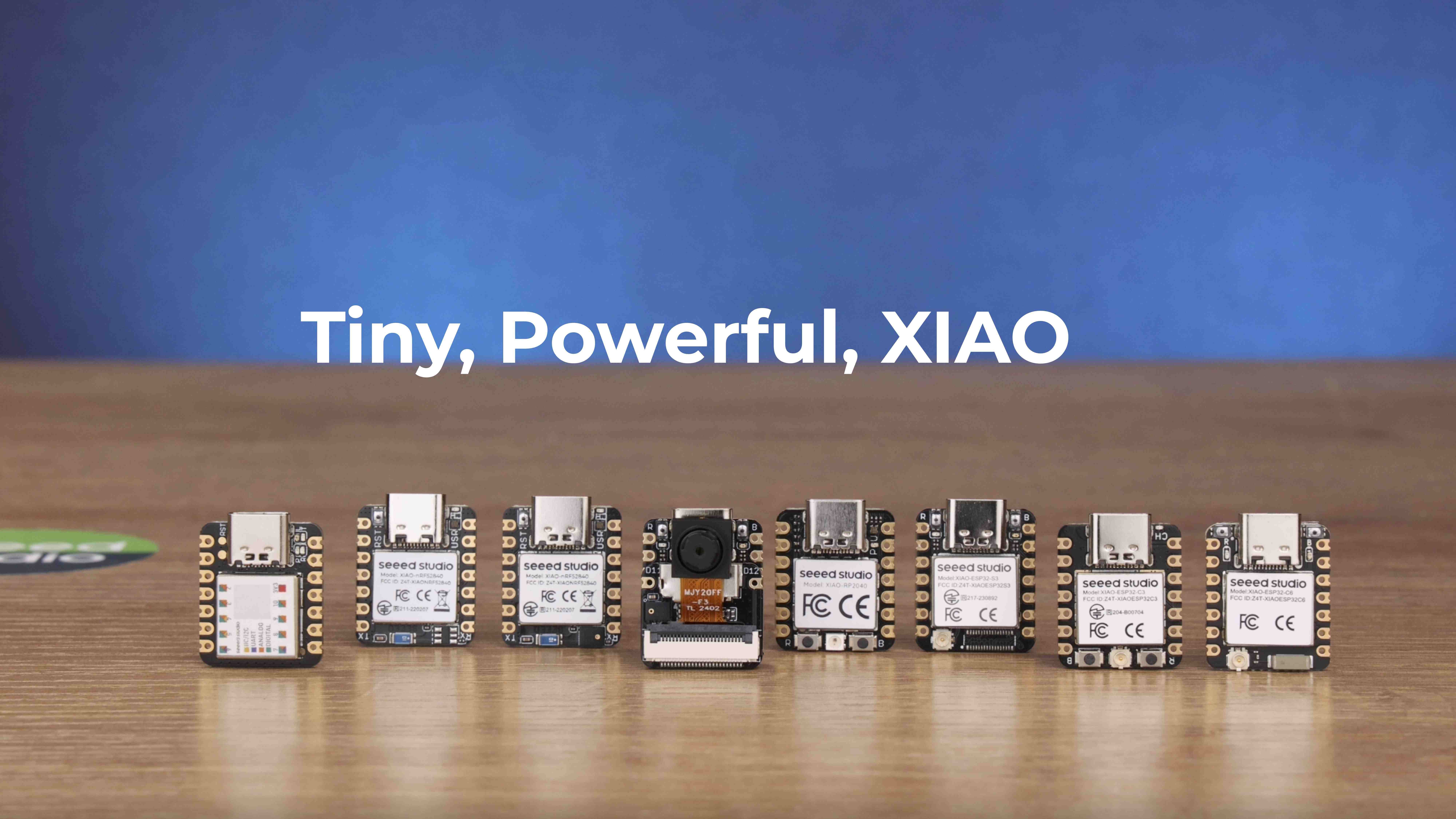 A lineup of the XIAO microcontroller dev boards with the text 'Tiny, Powerful, XIAO' above them. Each dev board is about a square and the size of a cheese-it with 7 pins on each side and a USB-C port on the top.